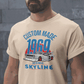 Man wearing beige Custom 1969 Iconic Skyline T-Shirt with vintage car graphic and blue-red text.