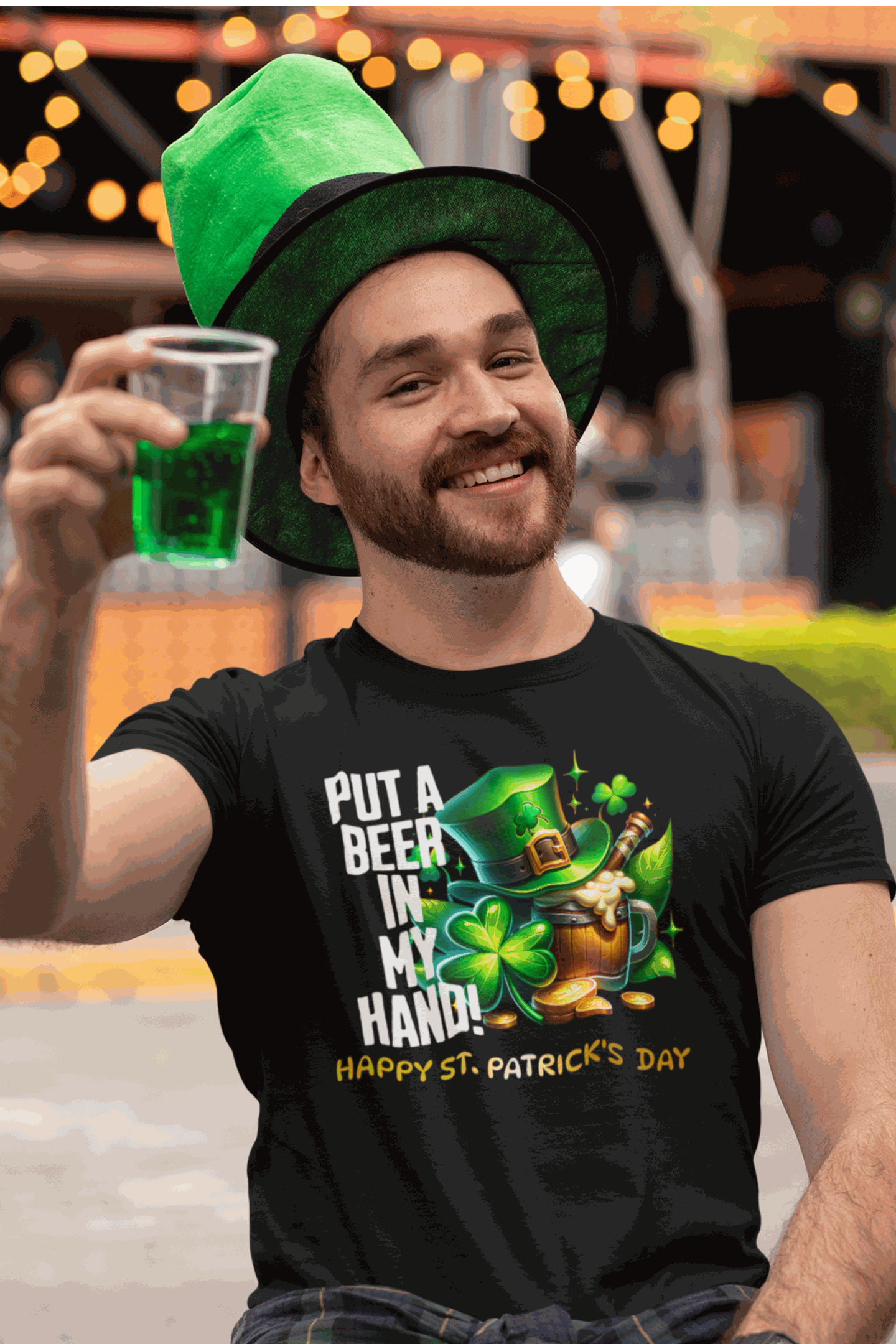 Man wearing St. Patrick's Day black tee with leprechaun and beer design holding green drink outdoors
